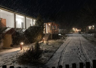 Esti kép a pihenőházról és az udvarról, ahol épp esik a hó.